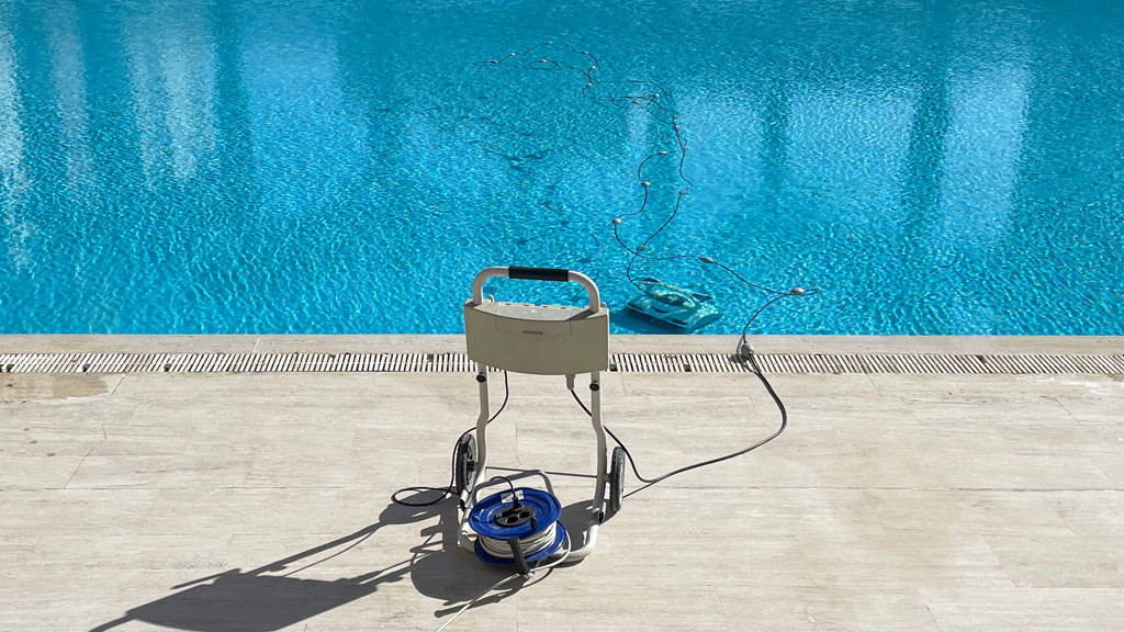 Propriétaire observant son robot piscine depuis la terrasse, équipement automatique bassin