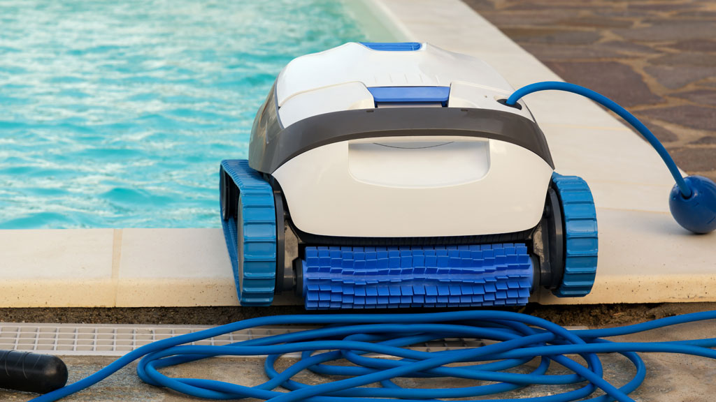 Accessoires piscine rangés en bord de bassin avec enrouleur bâche et épuisette, équipement entretien